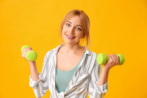 Ritratto di donna matura con manubri su sfondo a colori — Foto Stock