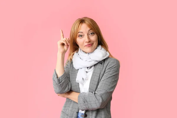 Stylish mature woman with raised index finger on color background — Stock Photo, Image