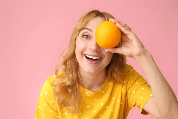 Stylish mature woman with orange on color background — Stock Photo, Image