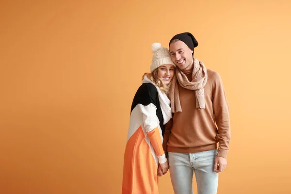 Счастливая молодая пара в теплой осенней одежде на цветном фоне — стоковое фото