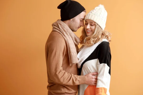 Happy young couple in warm autumn clothes on color background — Stock Photo, Image