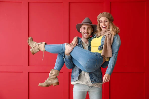 Feliz pareja joven en ropa de otoño caliente sobre fondo de color — Foto de Stock