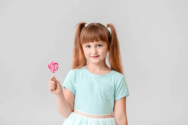 Cute little girl with lollipop on light background — Stock Photo, Image