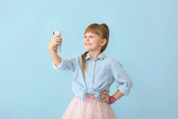 Söt liten flicka som tar selfie på färg bakgrund — Stockfoto