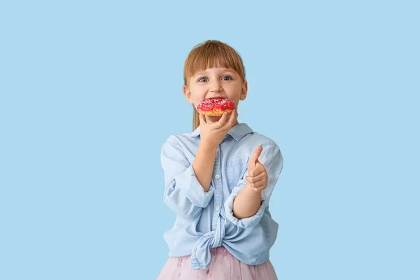 Cute little girl with tasty donut on color background — Stock Photo, Image