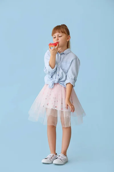 Cute little girl with tasty donut on color background — Stock Photo, Image