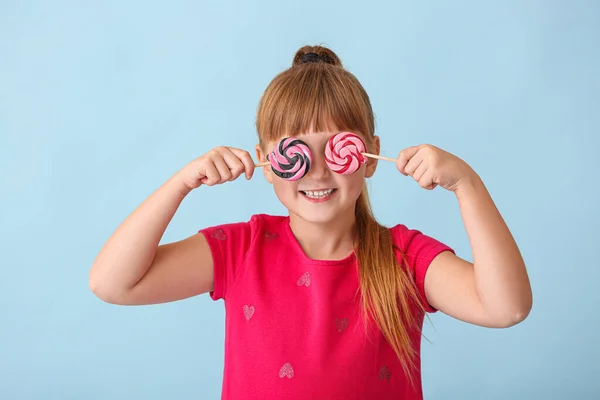 Menina bonito com pirulitos no fundo de cor — Fotografia de Stock