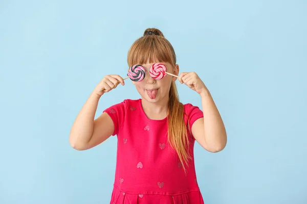 Menina bonito com pirulitos no fundo de cor — Fotografia de Stock