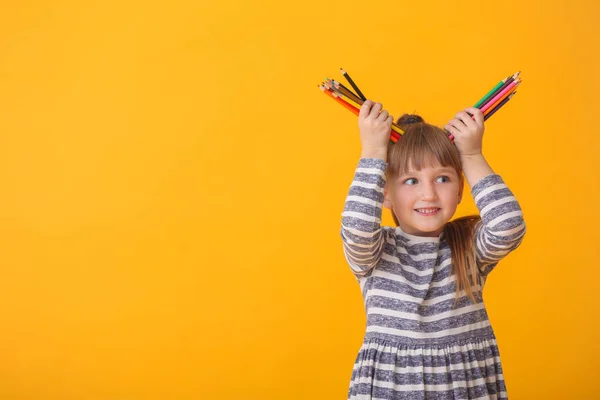 색 배경에 연필을 꽂고 있는 귀엽고 귀여운 소녀 — 스톡 사진