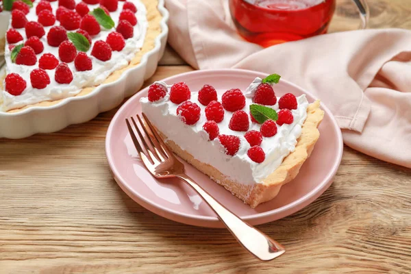 Placa con trozo de delicioso pastel de frambuesa sobre fondo de madera — Foto de Stock