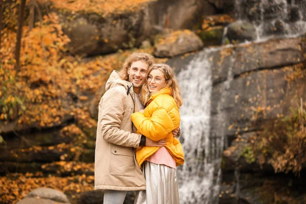 Young couple near waterfall in park on autumn day — Stock Photo, Image