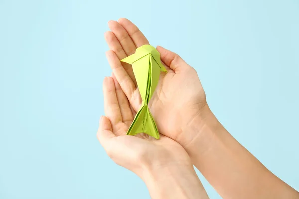 Female hands with origami fish on color background — Stock Photo, Image