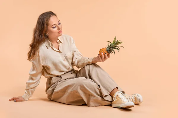 Portrait of fashionable young woman with pineapple on color background — Stock Photo, Image