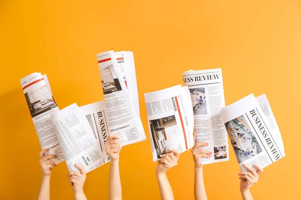 Руки женщины с газетами на цветном фоне — стоковое фото