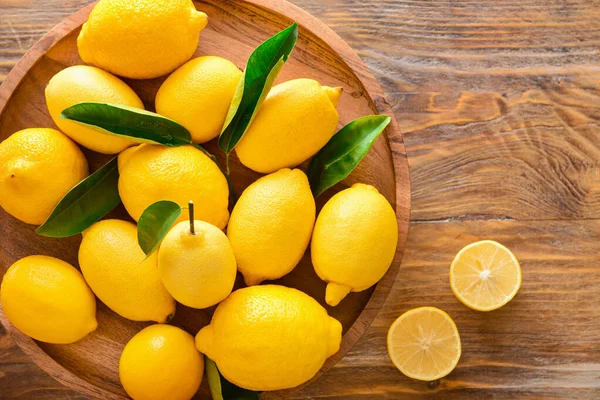 Plate with ripe lemons on wooden table — Stock Photo, Image