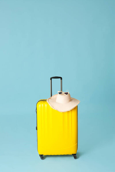 Packed suitcase, hat and glasses on color background. Travel concept