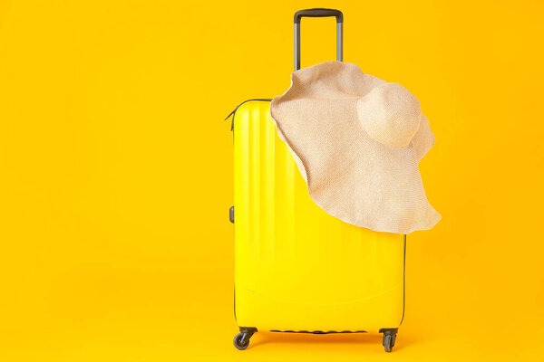 Packed suitcase and hat on color background. Travel concept