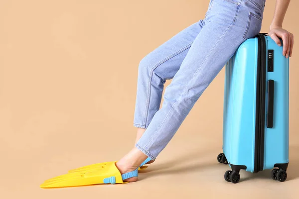 Woman in paddles and with suitcase on color background. Travel concept — Stock Photo, Image