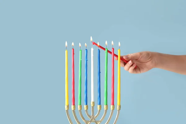 女性ライティングキャンドルでmenorahのためにHanukka上の色の背景 — ストック写真