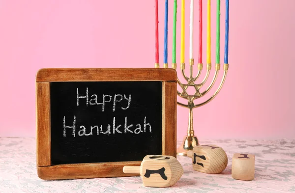 Dreidels, menorah en schoolbord met tekst Happy Hanukkah op tafel — Stockfoto