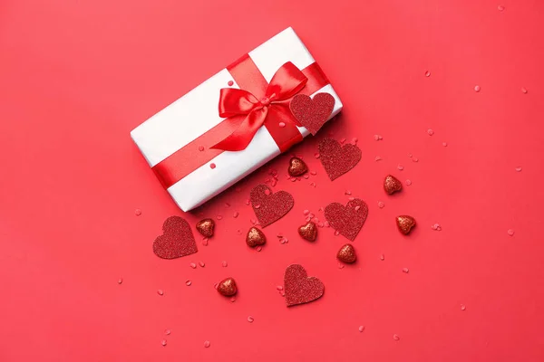 Geschenkbox zum Valentinstag und rote Herzen auf farbigem Hintergrund — Stockfoto