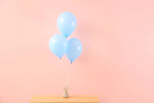 Air balloons with vase on table against color background — Stock Photo, Image