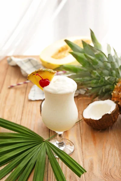 Glass of tasty Pina Colada cocktail and fruits on table — Stockfoto