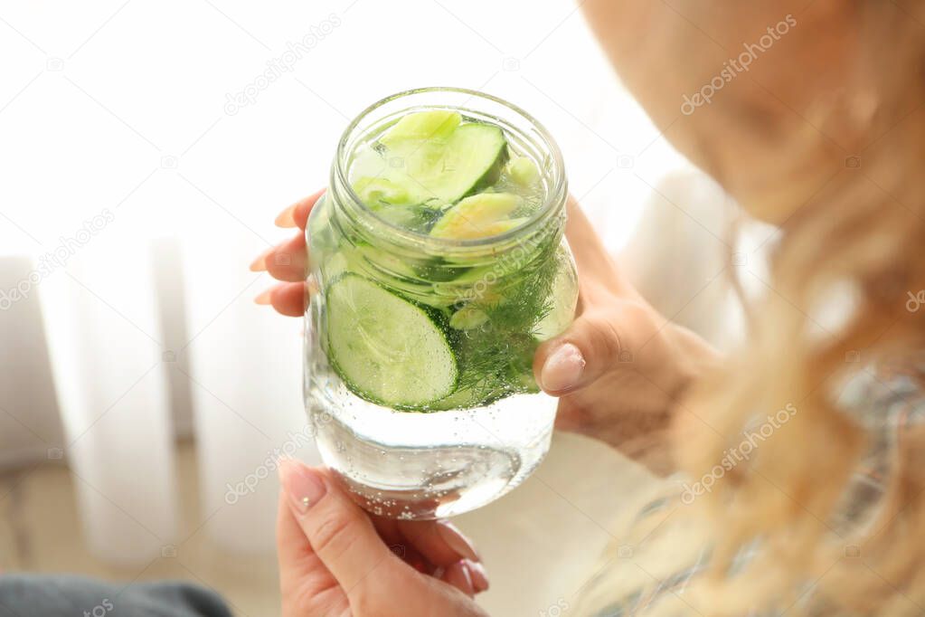 Woman with mason jar of healthy infused water at home