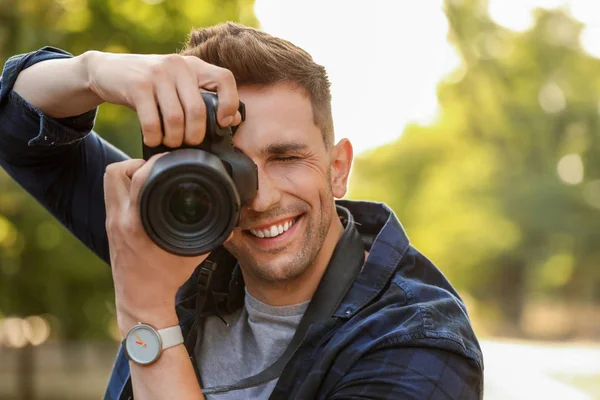 Knappe mannelijke fotograaf met camera buitenshuis — Stockfoto