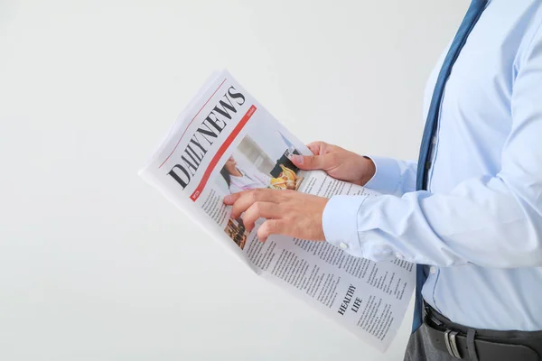 Handsome businessman with newspaper on light background — Stock Photo, Image