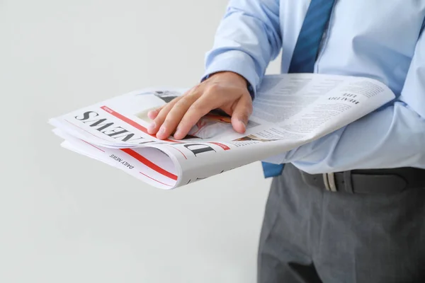 Handsome businessman with newspaper on light background, closeup — Stock Photo, Image