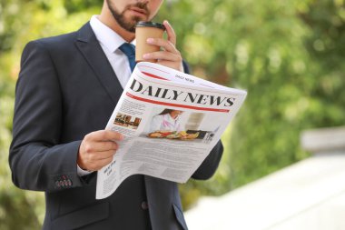 Gazetesi ve kahvesi olan yakışıklı bir iş adamı.