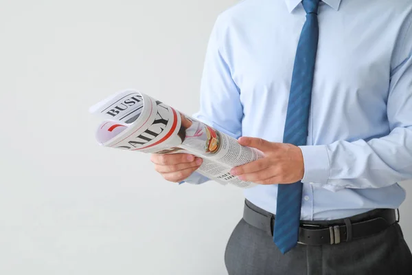 Schöner Geschäftsmann mit Zeitung auf hellem Hintergrund — Stockfoto