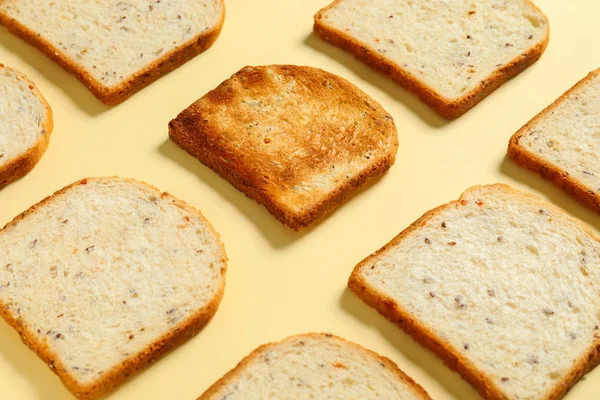 Ψημένο ψωμί ανάμεσα σε φρέσκα πάνω στο φόντο του χρώματος. Έννοια της μοναδικότητας — Φωτογραφία Αρχείου