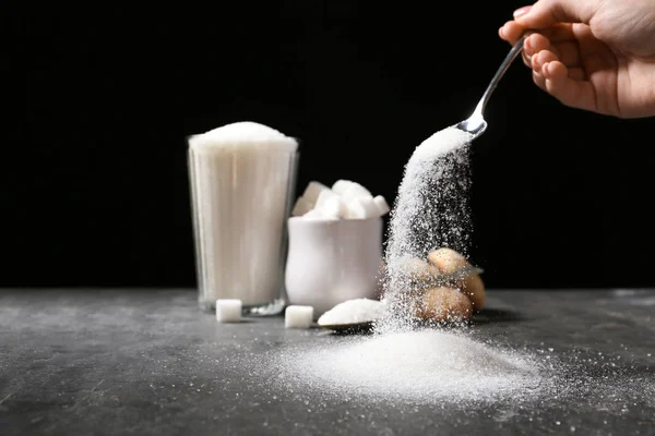 Donna versando zucchero dal cucchiaio sulla tavola — Foto Stock