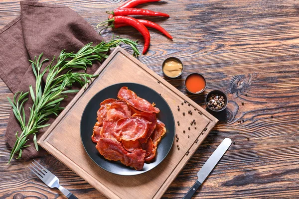 Assiette avec bacon frit savoureux sur table en bois — Photo