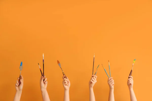 Руки женщины с принадлежностями художника на цветном фоне — стоковое фото