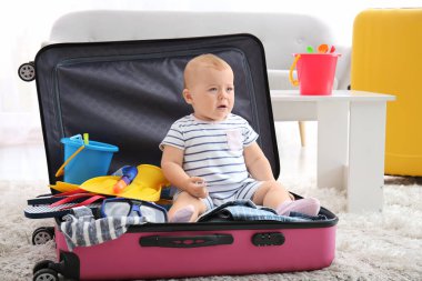 Evinde bavulu ve eşyaları olan sevimli bir bebek.