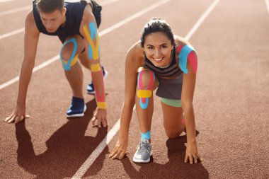 Crouch pozisyonunda fizyobantlı sportif çift stadyumda başlangıç pozisyonunda