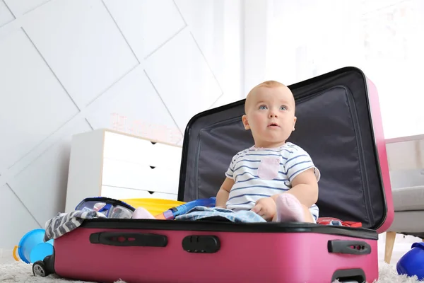Leuke baby met koffer en spullen thuis — Stockfoto