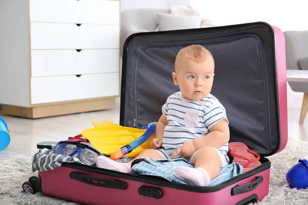 Симпатичный ребенок с чемоданом и вещами дома — стоковое фото