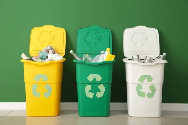 Containers with different types of garbage near color wall. Recycling concept — Stock Photo, Image