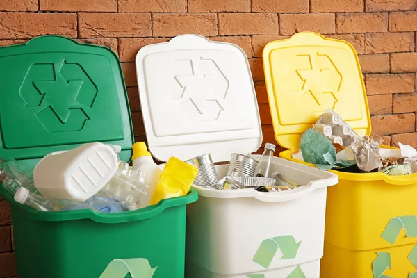 Containers with different types of garbage near brick wall. Recycling concept