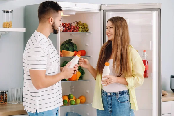 Молода пара бере їжу з холодильника на кухні — стокове фото