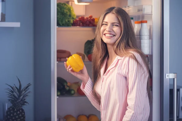 Mooie jonge vrouw het kiezen van voedsel in de koelkast 's nachts — Stockfoto