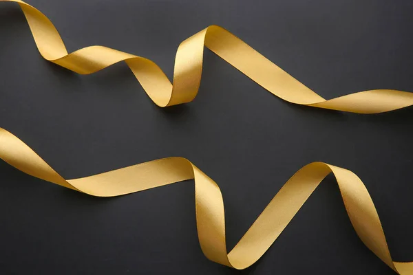 Beautiful golden ribbons on dark background — Stock Photo, Image