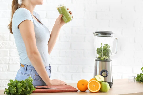 Mulher com smoothie caseiro saudável na cozinha — Fotografia de Stock