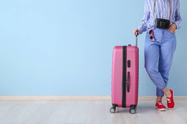Renkli duvarın yanında bavulu olan kadın. Seyahat kavramı