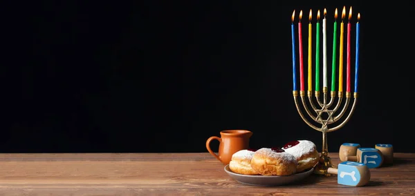 Minorca, dreidel e ciambelle per Hanukkah sul tavolo sullo sfondo scuro con spazio per il testo — Foto Stock