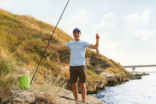 Молодой человек рыбачит на реке — стоковое фото